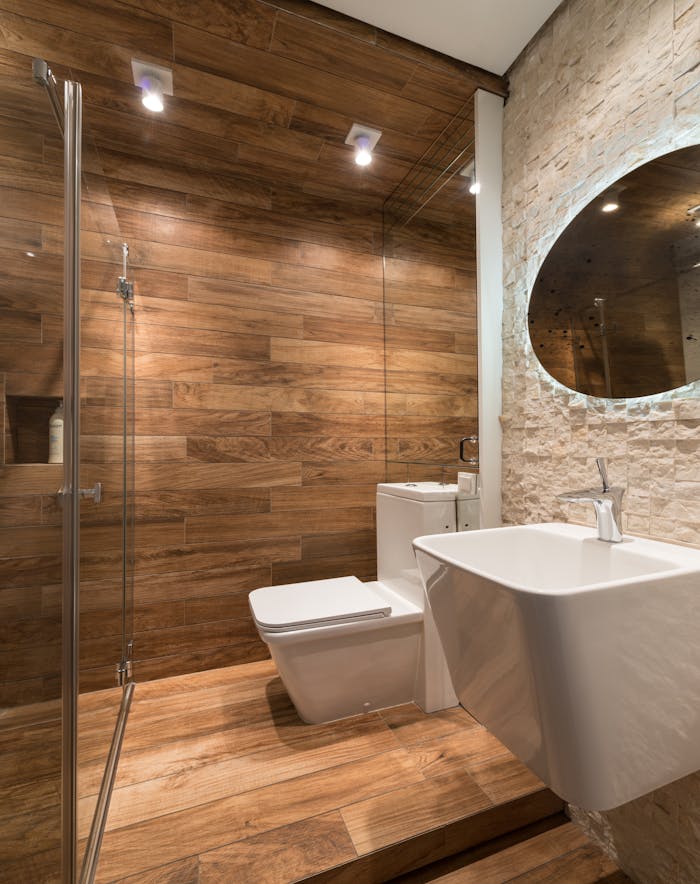 Modern stylish bathroom interior with wooden walls toilet bowl and washbasin under oval mirror